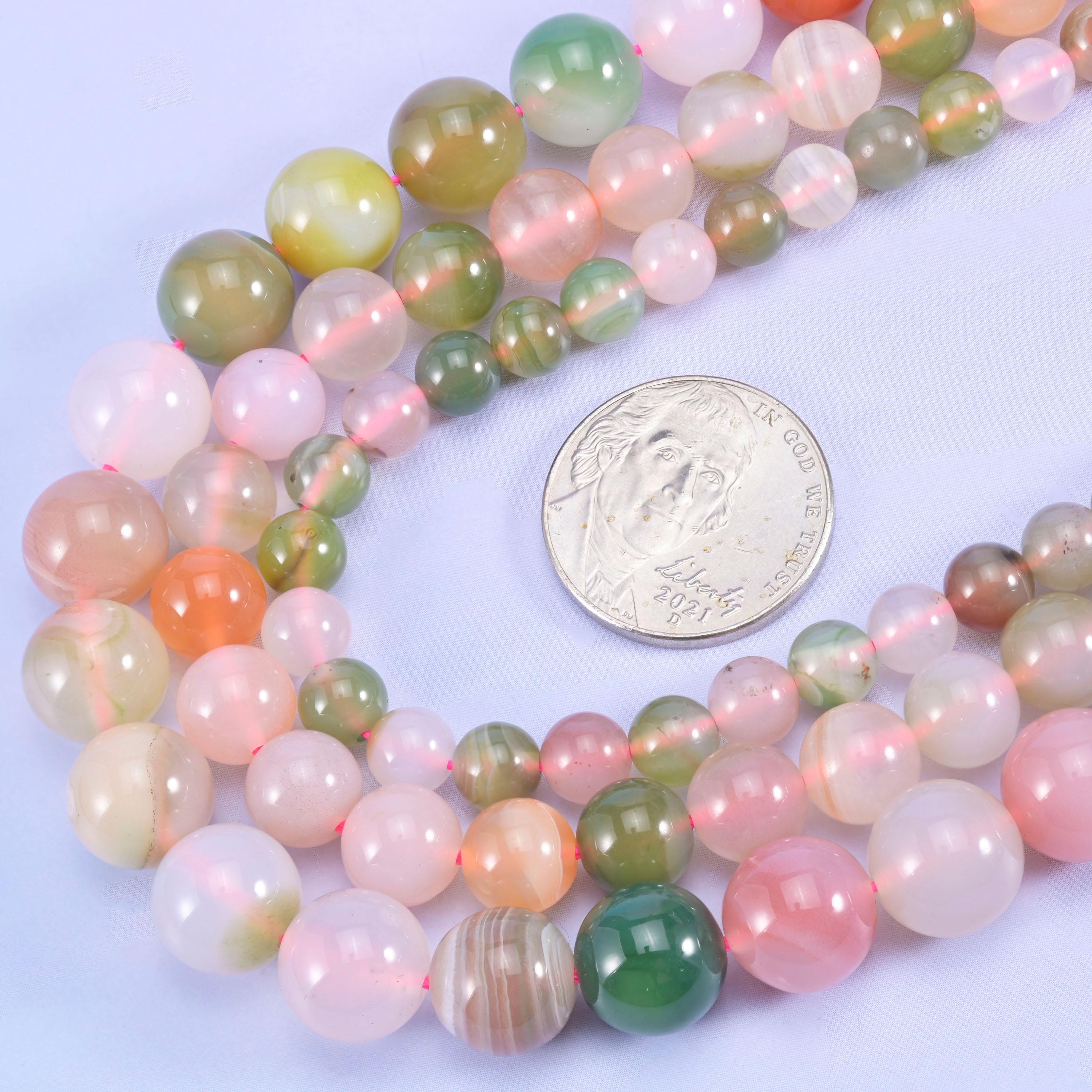 Multicolored round beads with a coin for size comparison on a light purple background